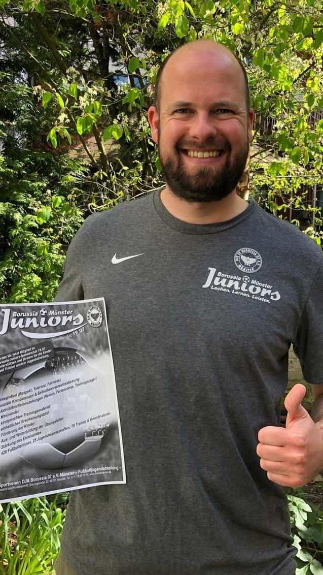 Lächelnder Mann in sportlichem T-Shirt, hält ein Informationsblatt über Tischtennis-Junioren im Grünen.