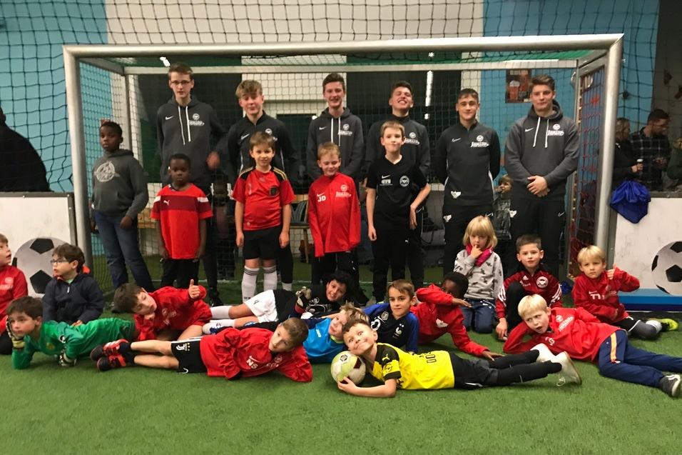 Gruppenfoto von Jungen in Sportkleidung vor einem Fußballtor in einer Halle, einige liegen auf dem Rasen, andere stehen.
