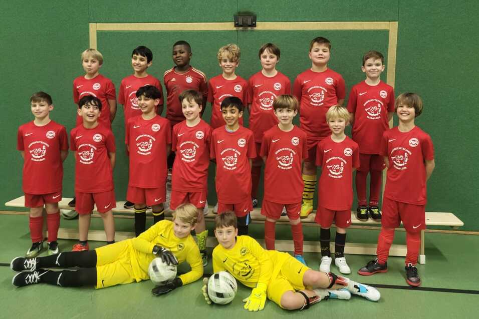 Gruppenupload von jungen Fußballspielern in roten Trikots, inklusive Torwart im gelben Trikot, vor einem Tor.