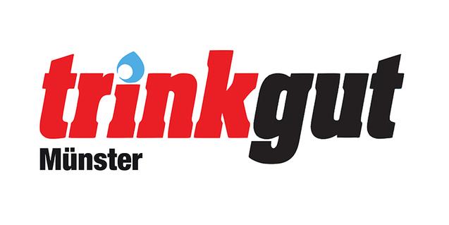 Logo von Trinkgut mit dem Schriftzug „trinkgut“ in rot und schwarz sowie dem Zusatz „Münster“ in schwarz.